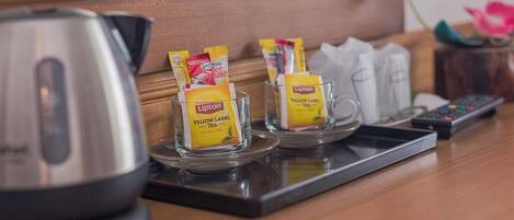 Quarto de hotel com estação de chá, incluindo sachês de chá Lipton Yellow Label, chaleira e controle remoto no balcão.
