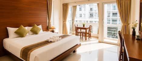 A hotel room with a large bed, a dining table, and a view of the city.