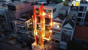 A multi-story building with a distinctive red and yellow facade, featuring a prominent circular logo and the name 'Pint Hotel'. - PYNT Hotel (Ho Chi Minh City)
