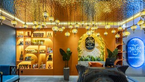 A hotel reception area with a modern design, featuring a reception desk, seating area, and a display of amenities. - PYNT Hotel (Ho Chi Minh City)