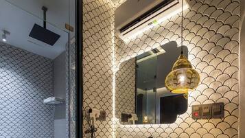 A modern bathroom with a glass partition, a toilet, a sink with a mirror, a pendant light, and a built-in television.