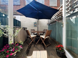 Enjoy dining or socializing in this outdoor patio area with a table and four chairs under a shaded umbrella.