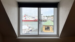 A window with a view of a harbor, including a large ship named 'RED FUNNEL' and a small building with a green roof. - Bell Cottage (Cowes)
