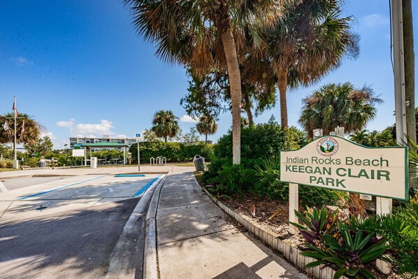 Señal para Indian Rocks Beach, Keegan Clair Park, con un área de estacionamiento y palmeras.