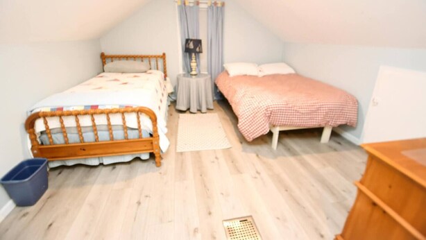 Ein Schlafzimmer mit zwei Betten, einem kleinen runden Tisch, einer blauen Mülltonne und einer Holzkommode.