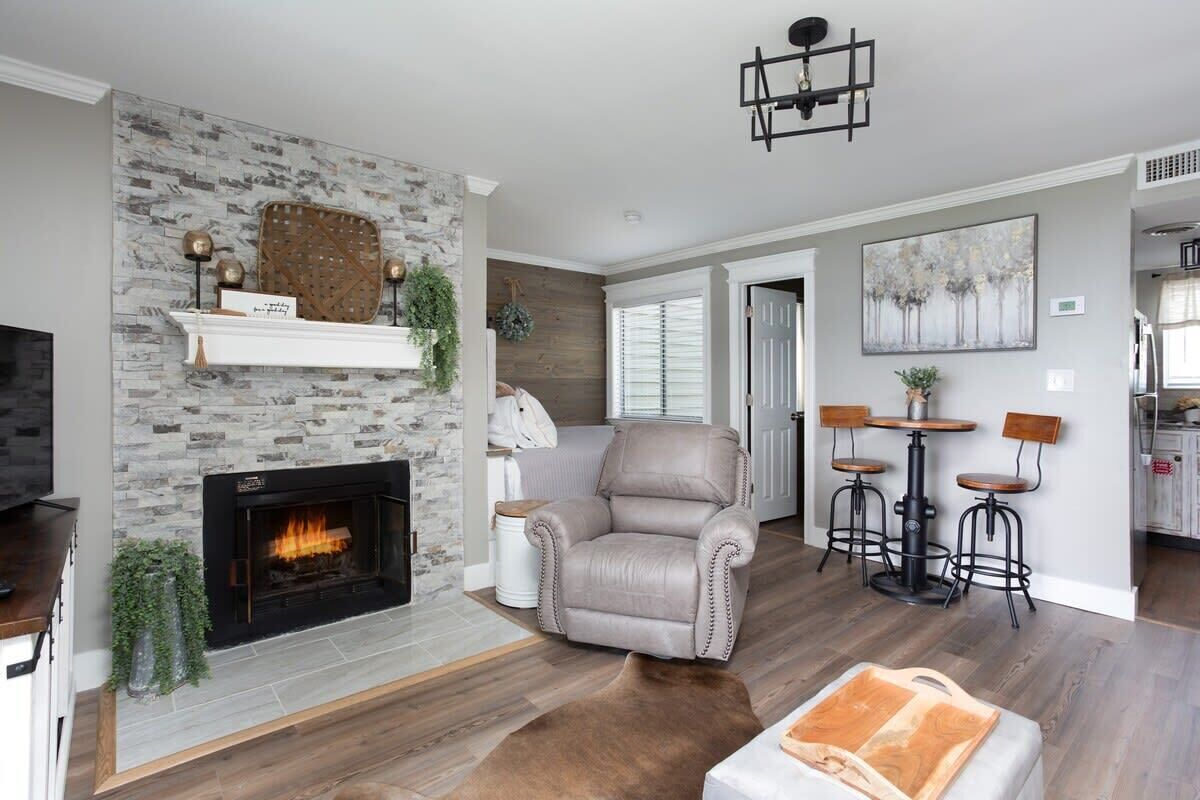A living room with a fireplace, a leather chair, and a bar area with stools.