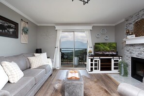 Ein Wohnzimmer mit einem grauen Sofa, einem Couchtisch und einem Kamin.