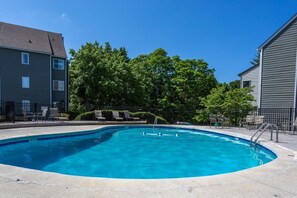 Una piscina con acqua cristallina e azzurra, circondata da lettini e una recinzione.