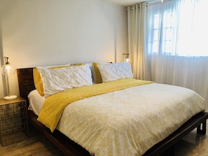 A neatly made bed with a yellow and white patterned bedspread, two bedside lamps, and a wooden headboard. - The Intercostal Condo (Hallandale Beach)