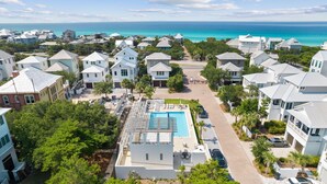 Un quartier résidentiel avec des maisons blanches, une piscine et une vue sur l’océan.
