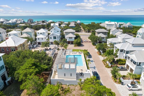 Un quartier résidentiel avec des maisons blanches, une piscine et une vue sur l’océan.