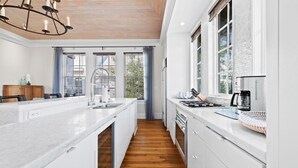 Une cuisine moderne avec des meubles blancs, un plancher en bois et une grande fenêtre qui laisse entrer la lumière naturelle.