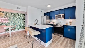 A modern kitchen with blue cabinets, a white island, and stainless steel appliances. - Beach Please 2BR Gulf Shores Oceanfront/Pool, Beach Please Beachfront condo sleeps 6 (Baldwin County)