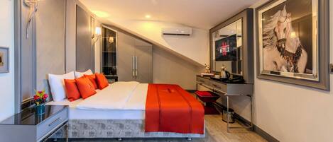A modern hotel room with a large bed, a desk, a mirror, and a TV.