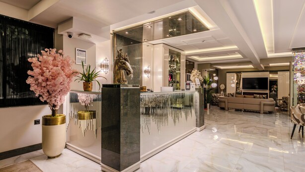 A modern lobby with a reception desk, a large potted plant, and a sofa in the background. - Atar Airport Hotel - Restaurant & Spa Wellness (Arnavutköy)