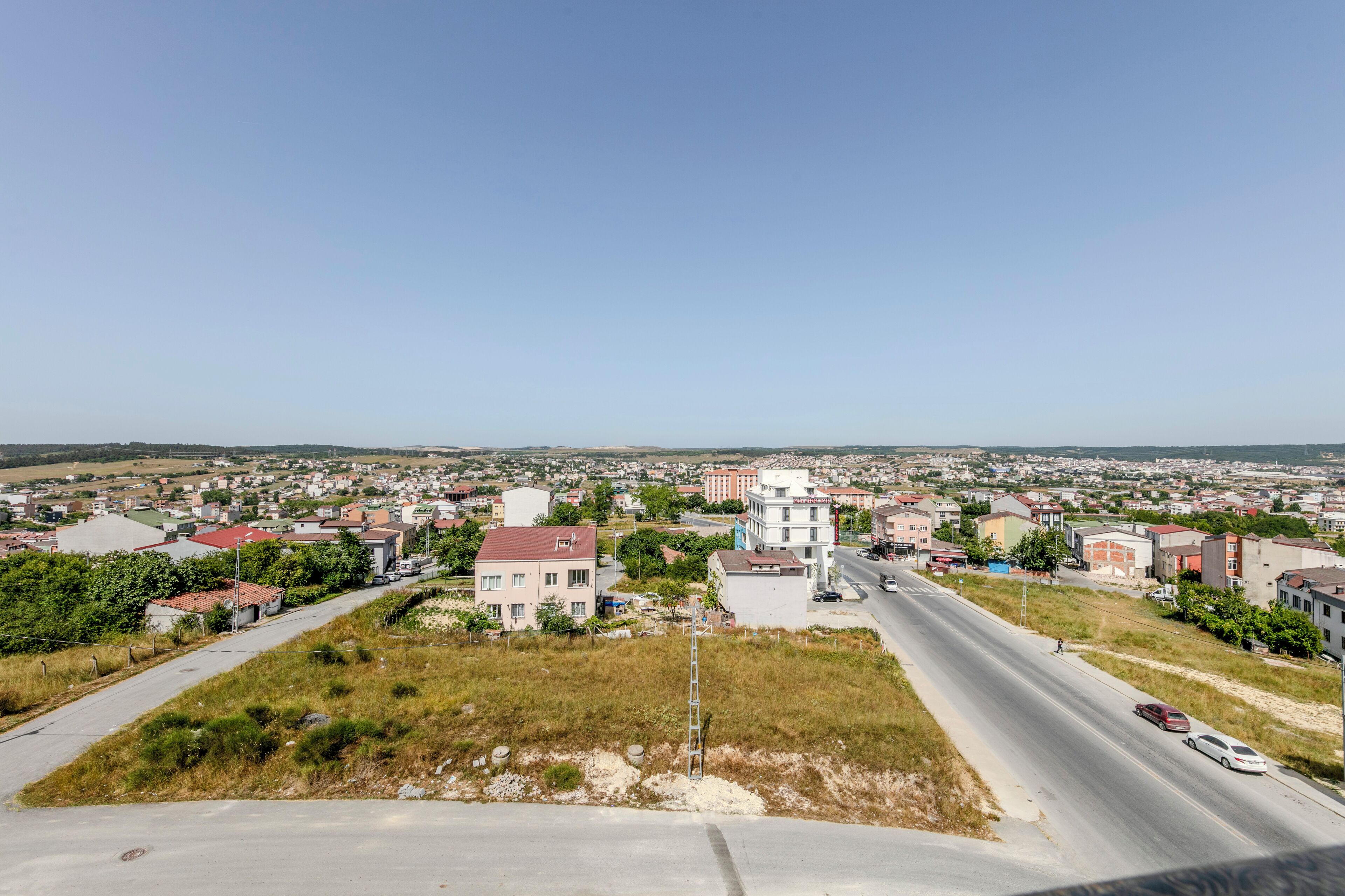 A wide road with buildings on both sides, a clear sky, and a distant view of a town.