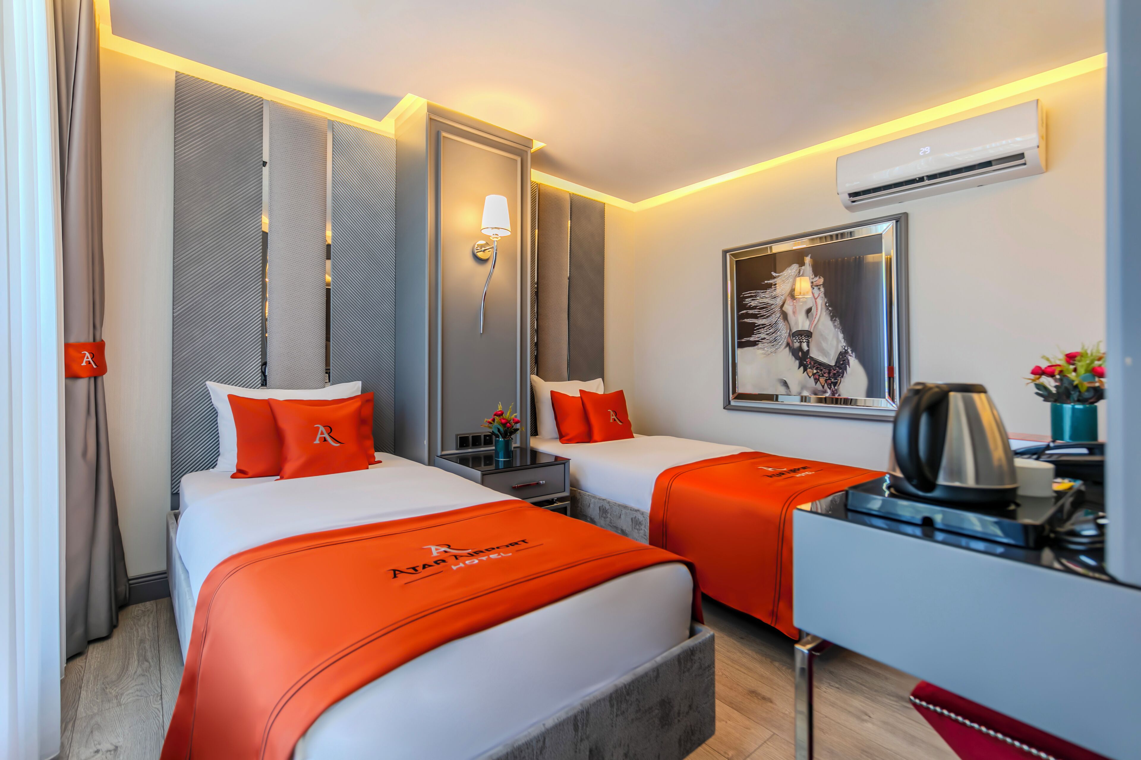 Habitación de hotel con dos camas, un escritorio, aire acondicionado y un cuadro en la pared.