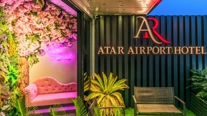 The exterior of Atar Airport Hotel with a pink floral wall, a neon sign, and a seating area. - Atar Airport Hotel - Restaurant & Spa Wellness (Arnavutköy)