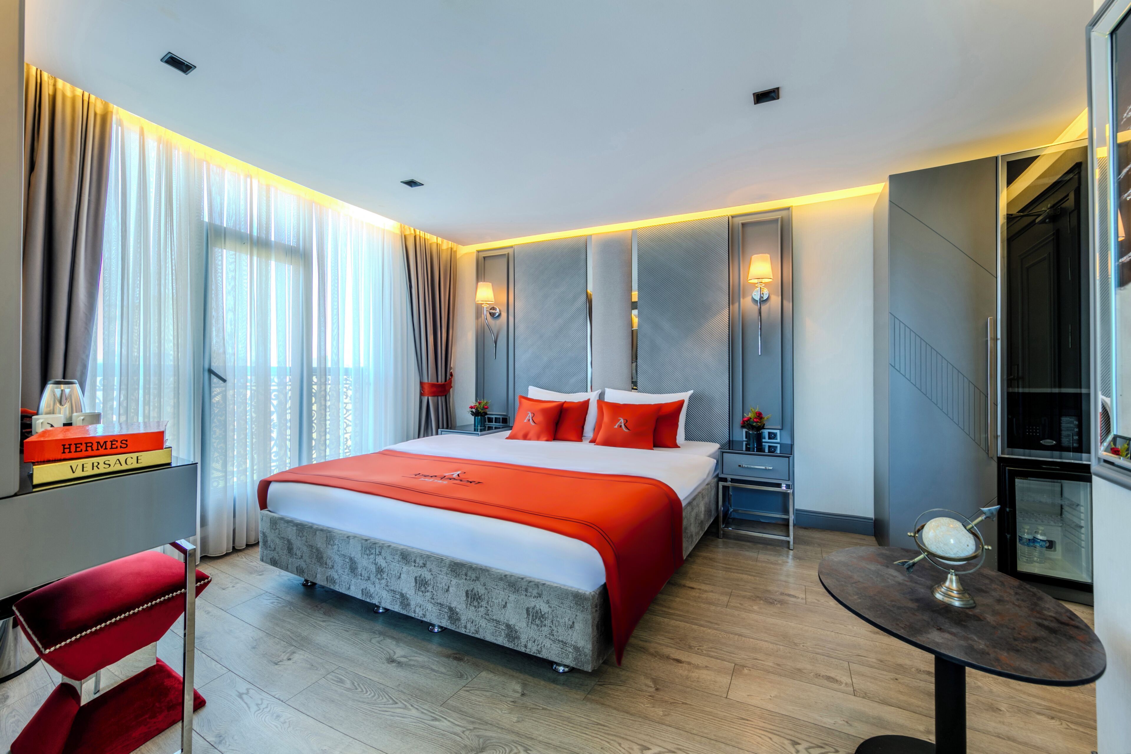 A modern hotel room with a large bed, a small table, and a desk.