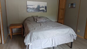 A bedroom with a bed, a nightstand, a wooden door, and a painting on the wall. - Gateway to keystone lake, Jellystone park , new mannford ramp& the harbor . (Mannford)