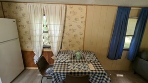 A compact room with a checkered table, a chair, a small table lamp, and a refrigerator. - Gateway to keystone lake, Jellystone park , new mannford ramp& the harbor . (Mannford)