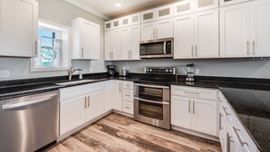 A modern kitchen with white cabinets, stainless steel appliances, and a black countertop.