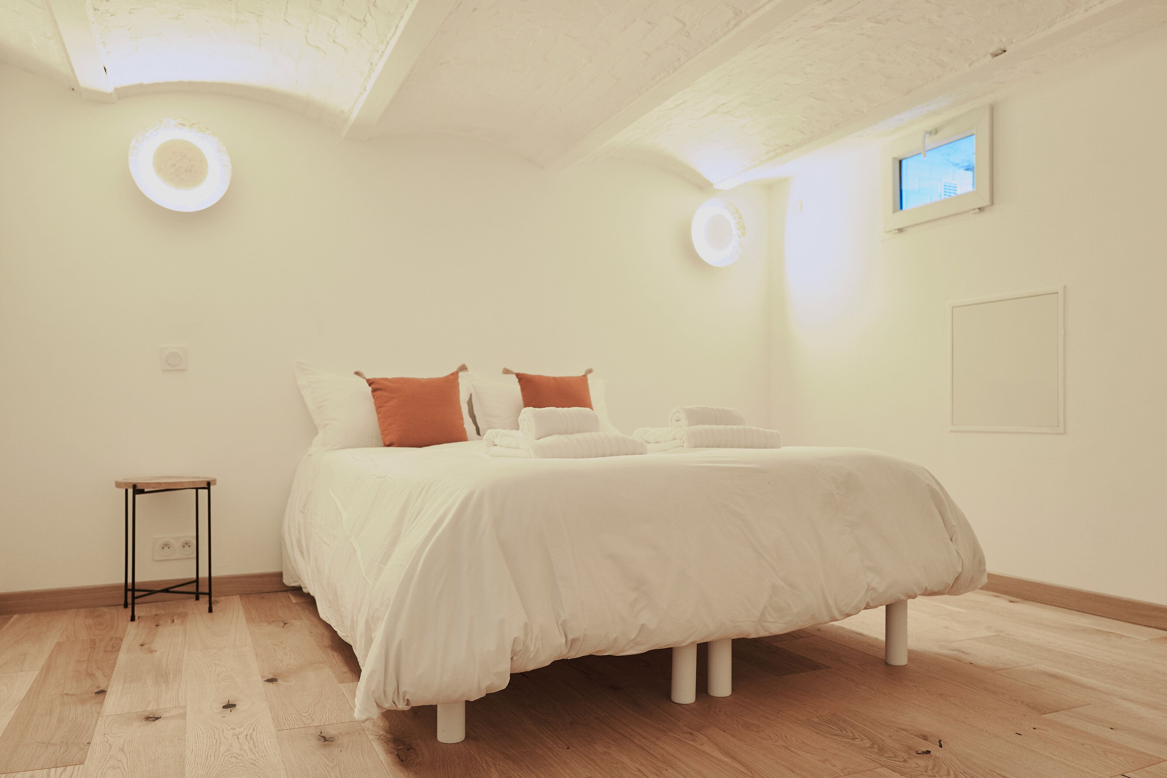 Een slaapkamer met een bed, een tafeltje en een raam.