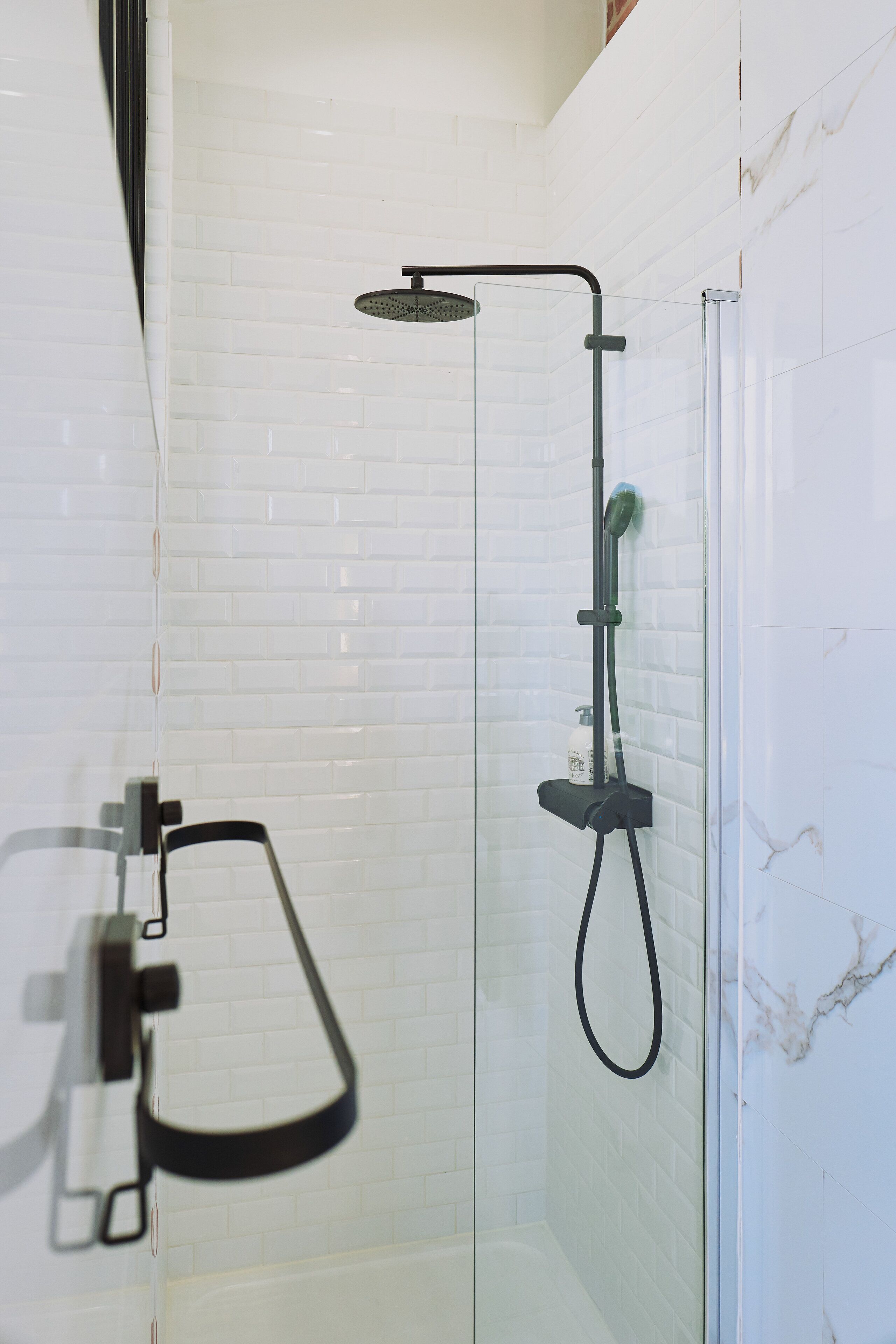 Eine Dusche mit Glasabtrennung, einer Handbrause und einer Handbürste.