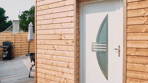 A wooden cabin with a white door and a small porch area.