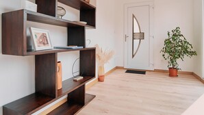 A modern interior with dark wooden shelves, a white door with a geometric design, and a potted plant.