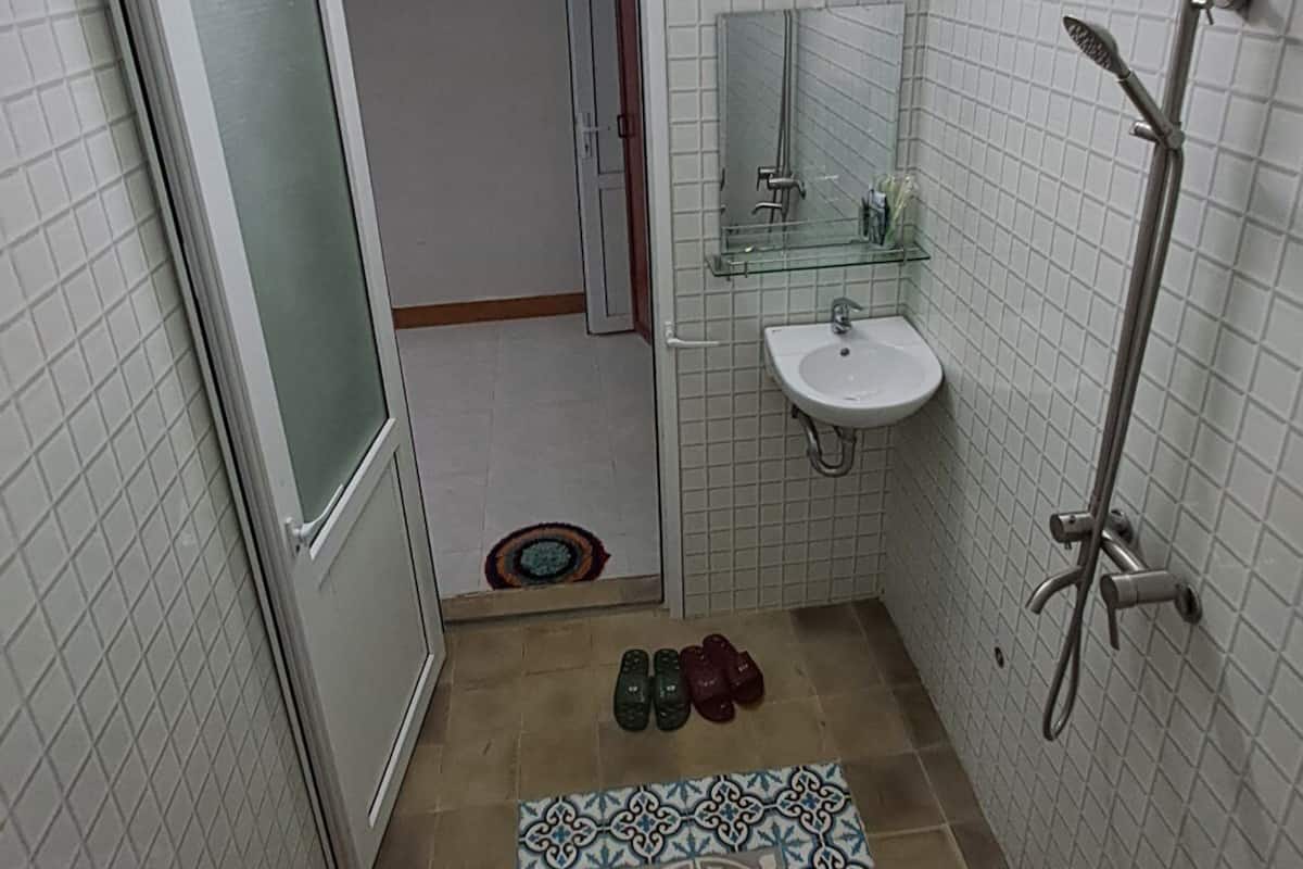 A compact bathroom with a shower, a sink, and a glass door leading to another room.