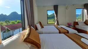 Een hotelkamer met twee bedden, grote ramen en uitzicht op bergen en groen.