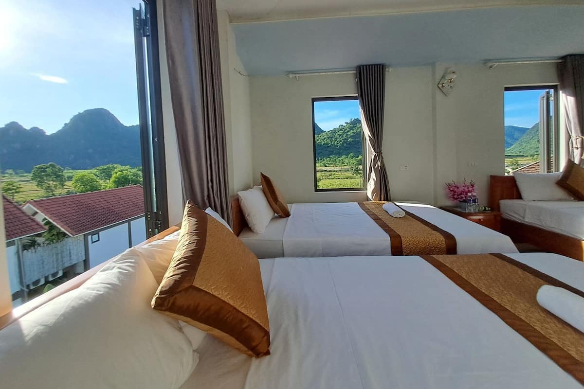 A hotel room with two beds, large windows, and a view of mountains and greenery.