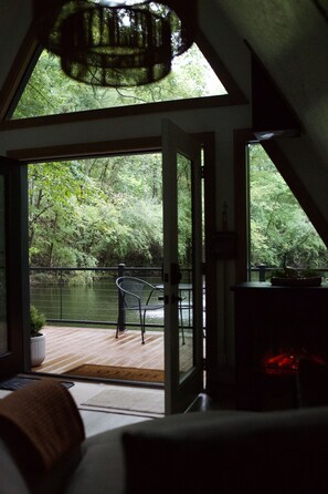 A room with a large glass door leading to an outdoor deck with a chair and a table.