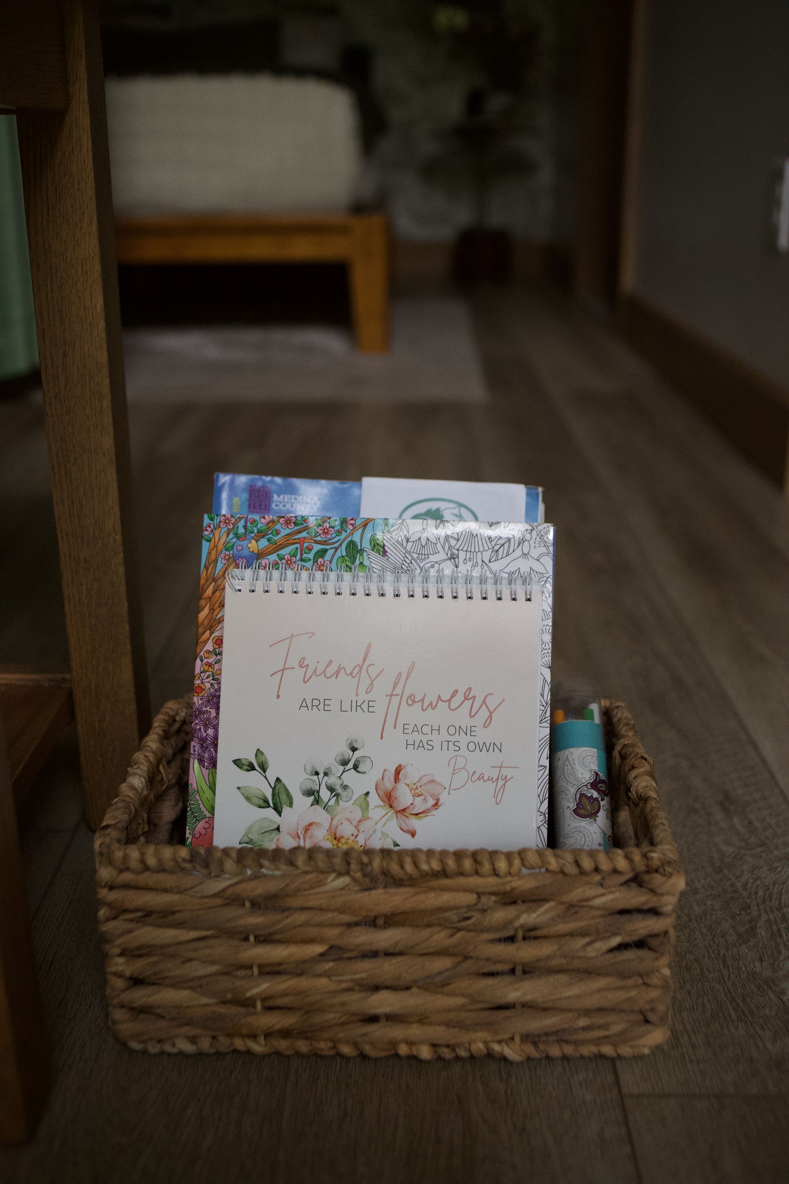 Ein Korbkobild mit einem Notizbuch mit floralen Mustern und einer Karte mit einem Zitat.