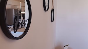 A wall with three circular mirrors of varying sizes, each with a rope handle. The largest mirror reflects a kitchen area with a refrigerator, microwave, and cabinets. - Aithrea s Homes in Pastida Rhodes (Rhodes)