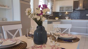 A dining area with a table set for four, including plates, cutlery, and a vase with flowers. - Aithrea s Homes in Pastida Rhodes (Rhodes)