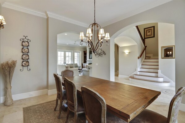 Enjoy meals in this dining area with a large table and six chairs, surrounded by decorative wall art and a chandelier.