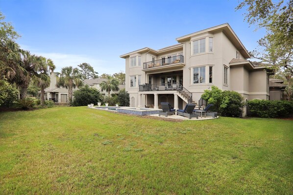 A two-story house with a large front yard, a swimming pool, and a balcony.