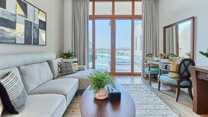 A modern living room with a sofa, coffee table, and dining area. - bnbme | Palm Views West | STUDIO (Dubai)