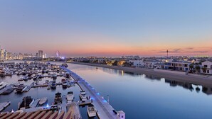 A marina with boats docked, a waterfront promenade, and buildings in the background. - bnbme | Palm Views West | STUDIO (Dubai)