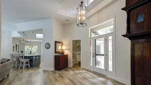 A spacious hallway with hardwood flooring, a dining area with a bar, and a large wooden cabinet. - Sunset Rentals | Kingston 47 (Hilton Head Island)
