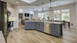 A spacious kitchen with a large island, modern appliances, and pendant lighting. - Sunset Rentals | Kingston 47 (Hilton Head Island)