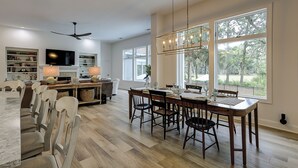 A spacious kitchen with a dining area, large windows, and a modern chandelier. - Sunset Rentals | Kingston 47 (Hilton Head Island)