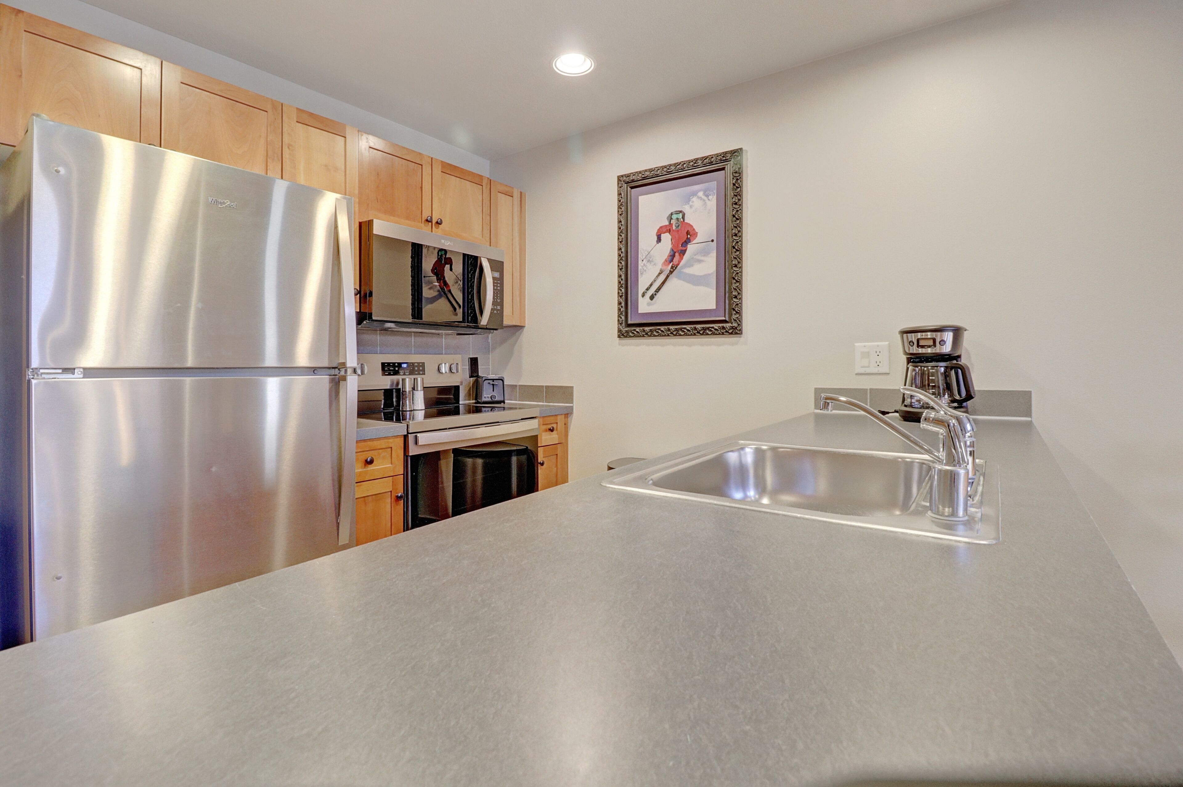 A modern kitchen with stainless steel appliances, wooden cabinets, and a large sink.