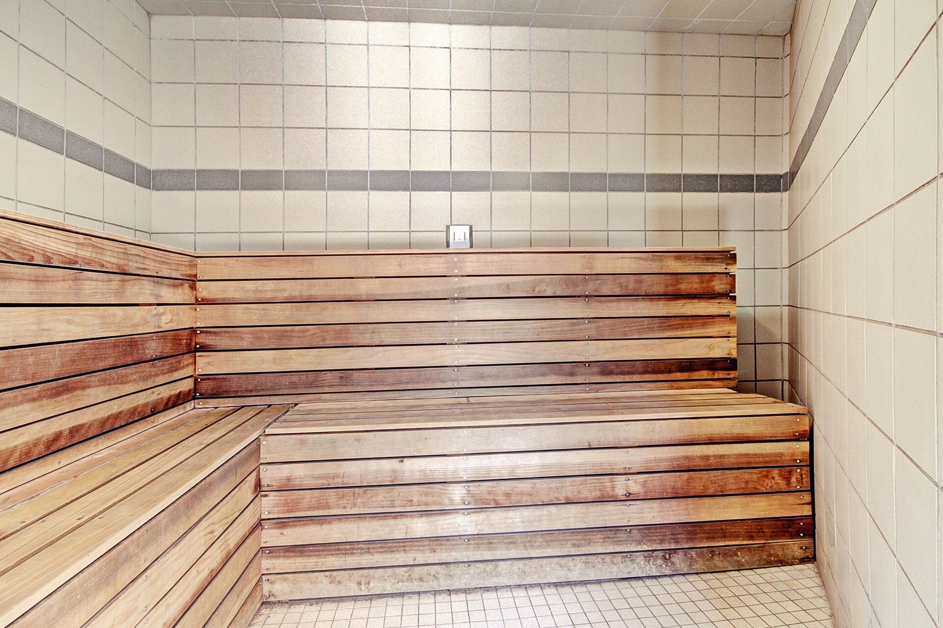 Una sauna con panche in legno e pareti piastrellate.