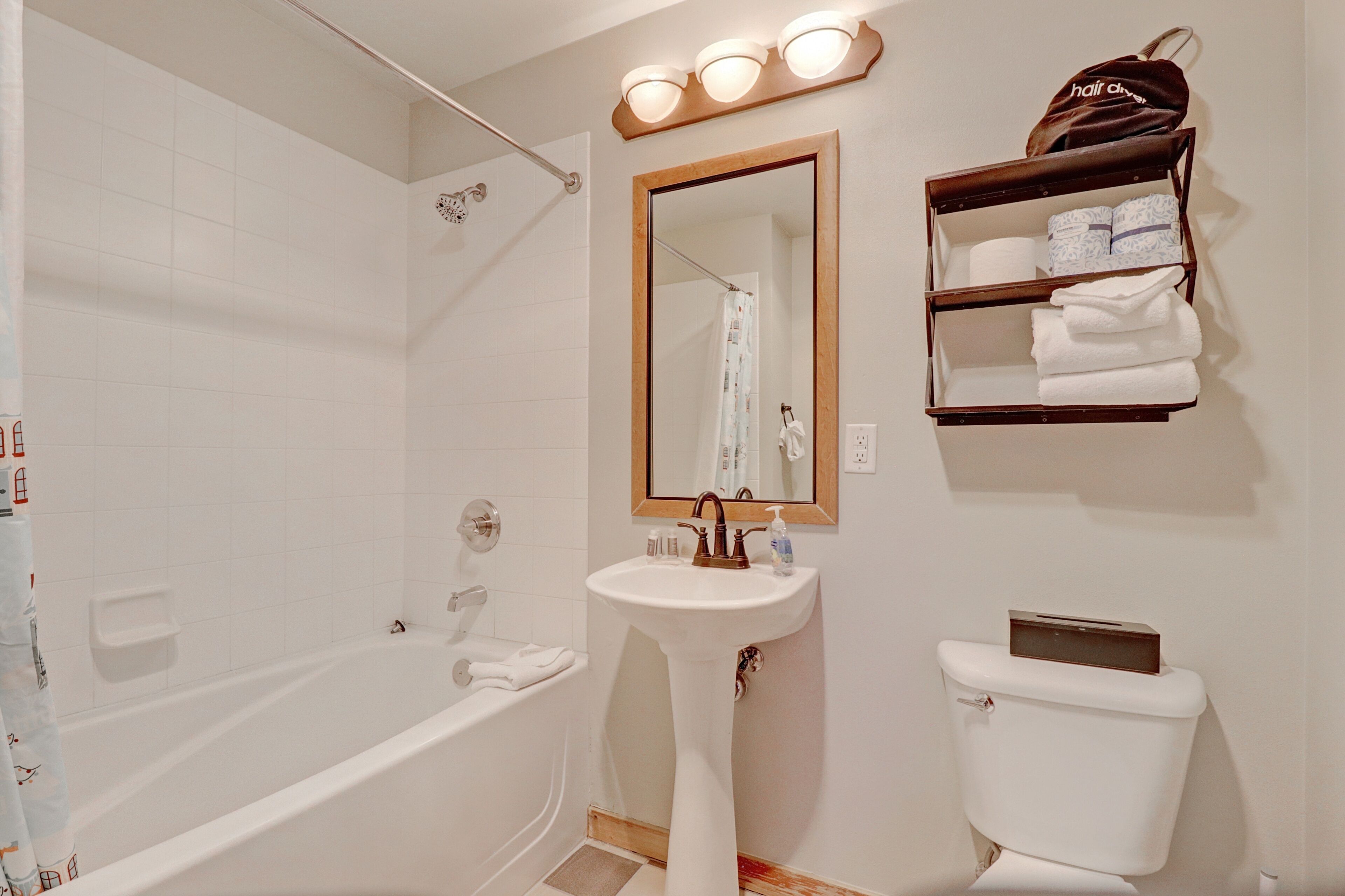 A bathroom with a bathtub, a sink, a toilet, and a mirror.