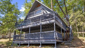 A multi-level wooden cabin with a balcony on each floor, surrounded by trees. - Marina Beach Cabin - Dog-Friendly Home with Deck! by Yosemite Region Resorts (Groveland)