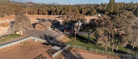 A large equestrian facility with multiple riding arenas, stables, and a fenced perimeter.