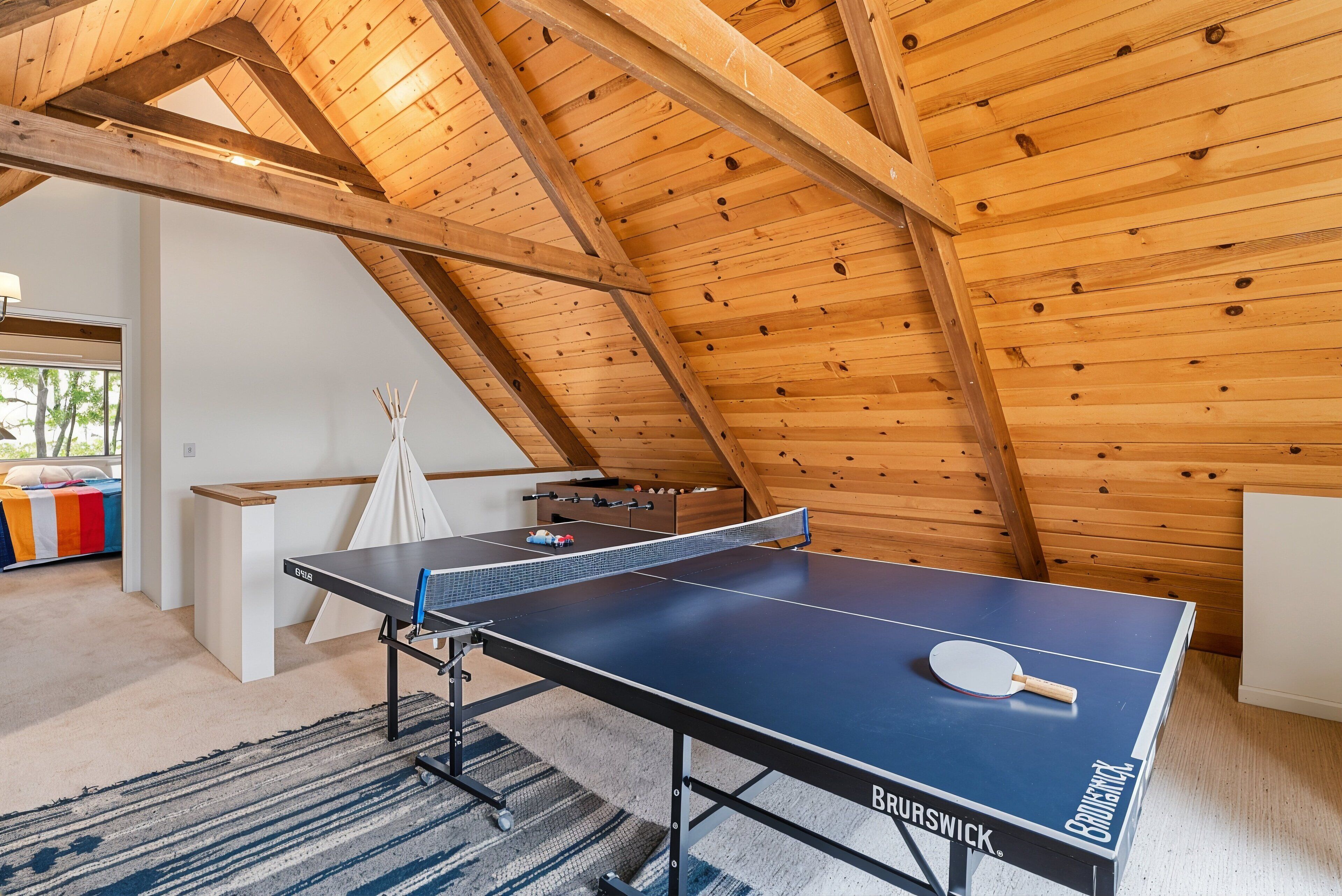 Et bordtennisbord i et rum med træbjælker i loftet.